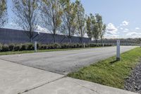 a large parking lot with lots of trees around it and a sidewalk in front of the building