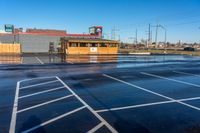 empty parking lot with red and blue buildings in the back ground and traffic lights on