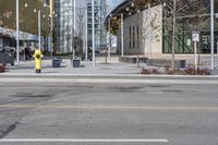 yellow fire hydrant in the middle of a city road surrounded by tall buildings with windows