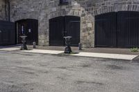 three parking meters sitting next to each other in a parking lot with brick walls and doors