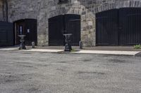 three parking meters sitting next to each other in a parking lot with brick walls and doors