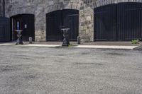 three parking meters sitting next to each other in a parking lot with brick walls and doors