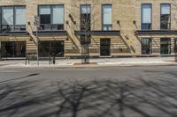 a building with windows and trees on a street in front of it with snow and no leaves