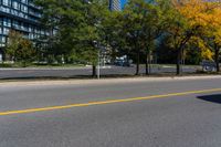 a road with cars in it and a yellow line on the street behind it, in front of a large building