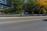 a road with cars in it and a yellow line on the street behind it, in front of a large building