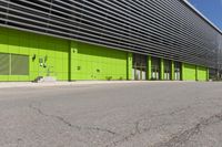 an empty road is outside of a green building with some green shutters on it