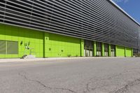 an empty road is outside of a green building with some green shutters on it