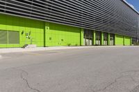 an empty road is outside of a green building with some green shutters on it