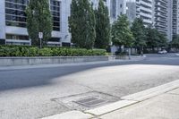 a car driving down an empty street lined with tall buildings and trees in the background