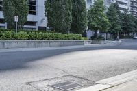 a car driving down an empty street lined with tall buildings and trees in the background