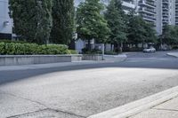 a car driving down an empty street lined with tall buildings and trees in the background