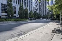 a car driving down an empty street lined with tall buildings and trees in the background