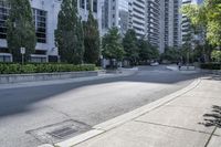 a car driving down an empty street lined with tall buildings and trees in the background