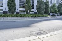 a car driving down an empty street lined with tall buildings and trees in the background