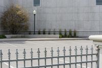 a building with parking lot and several windows on it's facade as seen through a wrought iron fence