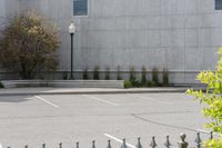 a building with parking lot and several windows on it's facade as seen through a wrought iron fence