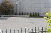 a building with parking lot and several windows on it's facade as seen through a wrought iron fence