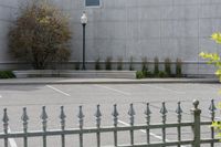 a building with parking lot and several windows on it's facade as seen through a wrought iron fence