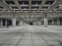 empty open air office space in a large building with concrete columns and ceiling lighting around