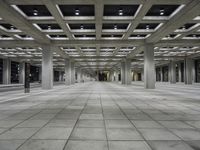 empty open air office space in a large building with concrete columns and ceiling lighting around