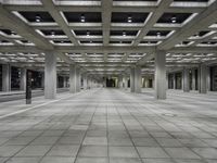 empty open air office space in a large building with concrete columns and ceiling lighting around