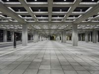 empty open air office space in a large building with concrete columns and ceiling lighting around