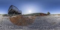 a half circular picture of an open air tunnel in the desert and dirt mound with a ramp