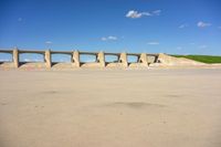 an empty concrete slab, with several pillars and arches, with blue skies and white clouds