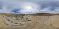 a picture of an open desert landscape with rocks and dirt and clouds in the sky