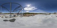 a 360 - pane view from underneath a metal structure of a water tower in an open field