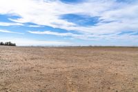 an empty land with lots of barren dirt and sparse grass at the back, and mountains in the background