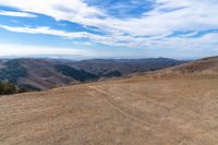 an open mountain with dirt roads leading into the mountains and a wide view of the landscape