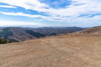 an open mountain with dirt roads leading into the mountains and a wide view of the landscape