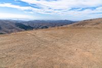 an open mountain with dirt roads leading into the mountains and a wide view of the landscape