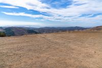 an open mountain with dirt roads leading into the mountains and a wide view of the landscape