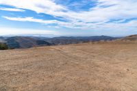 an open mountain with dirt roads leading into the mountains and a wide view of the landscape