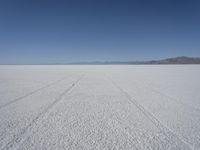 the vast open plain on a clear day with snow on the ground and mountains in the background