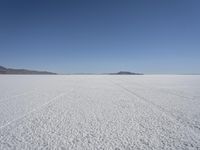 the vast open plain on a clear day with snow on the ground and mountains in the background