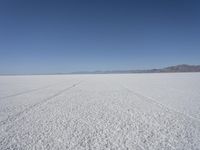 the vast open plain on a clear day with snow on the ground and mountains in the background