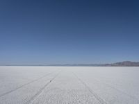 the vast open plain on a clear day with snow on the ground and mountains in the background