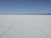 the vast open plain on a clear day with snow on the ground and mountains in the background