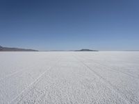 the vast open plain on a clear day with snow on the ground and mountains in the background