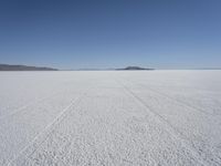 the vast open plain on a clear day with snow on the ground and mountains in the background