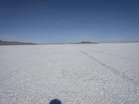 the vast open plain on a clear day with snow on the ground and mountains in the background