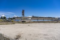 a picture of the dirt outside a stadium with some water in the background and an open area behind it