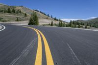 the open road with yellow stripe on the edge is surrounded by trees and snow capped mountains