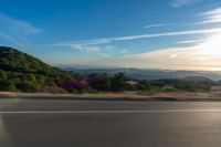 a car going down an open road during the day time and mountains in the distance