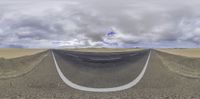 an open road stretching through the desert with clouds and a sky background are viewed in this fish - eye image