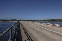 a man riding a horse on top of a bridge next to water under a blue sky