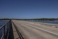 a man riding a horse on top of a bridge next to water under a blue sky